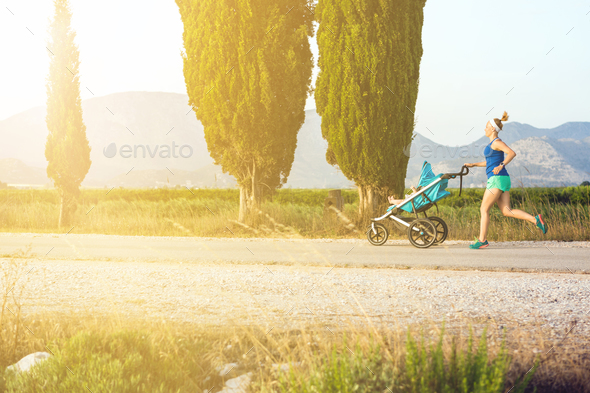 Running mother with stroller enjoying motherhood at sunset lands - Stock Photo - Images