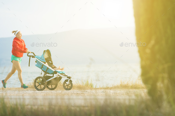 Running mother with baby stroller enjoying sunset landscape - Stock Photo - Images