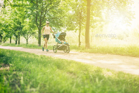 Running woman with baby stroller enjoying summer in park - Stock Photo - Images