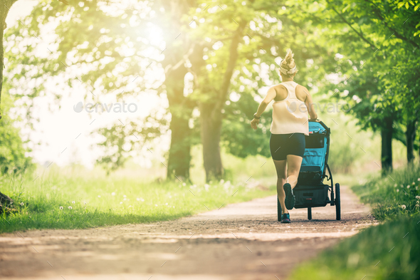 Running woman with baby stroller enjoying summer in park Stock Photo by blas