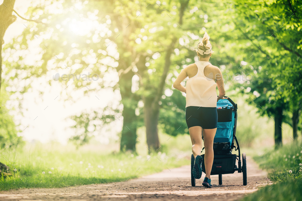 Running woman with baby stroller enjoying summer in park - Stock Photo - Images