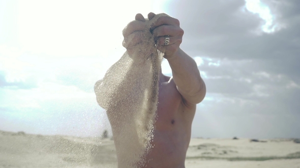 Man Pours Sand Through His Fingers