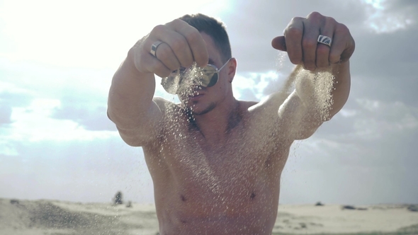 Man Pours Sand through His Fingers alt