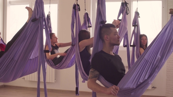 Group of People Doing Aerial Yoga Asanas in Gym