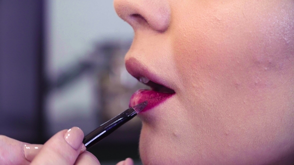 Makeup Artist Applying Pink Lipgloss on the Lips