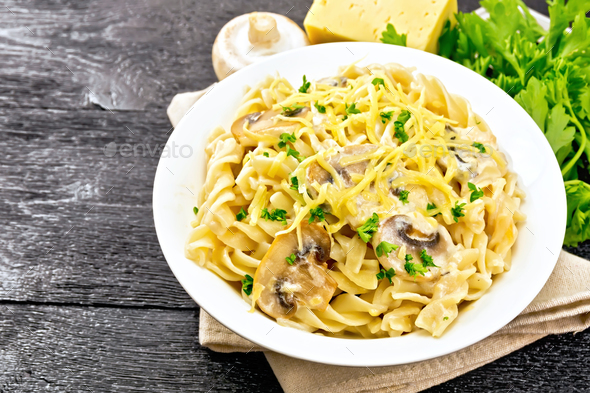 Fusilli with mushrooms and cream in plate on board - Stock Photo - Images
