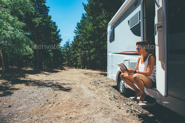 Girl reads on a motor home door step - Stock Photo - Images