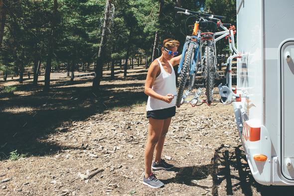 Girl is taking a bicycle from the motor home - Stock Photo - Images