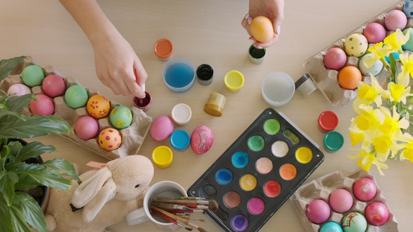 Woman Paints Rabbit on Colored Eggs at Easter Holiday alt