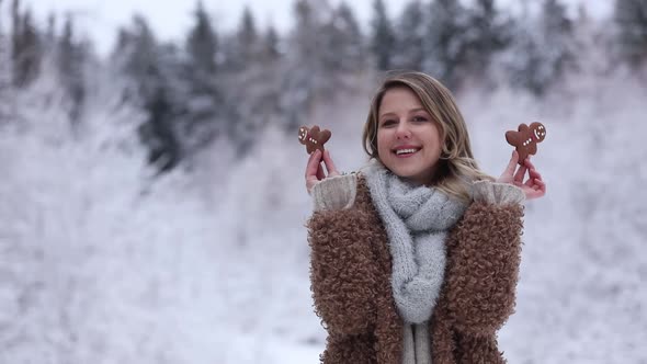 Beautiful girl in coat with cookie in a snow forest.