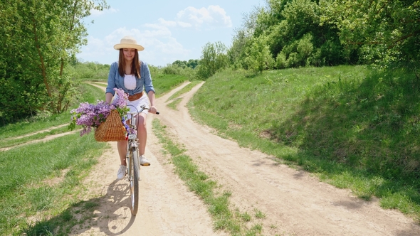 Cute Girl in a Hat on a Bicycle Traveling in Nature alt