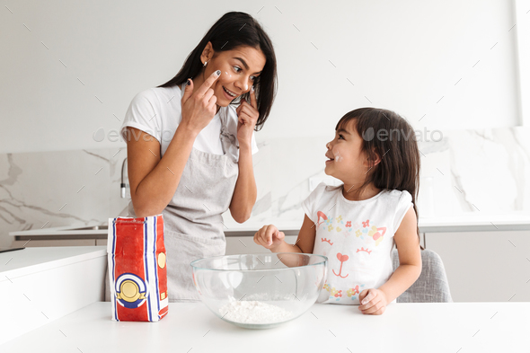 Happy brunette woman wearing apron cooking with her little daugh - Stock Photo - Images