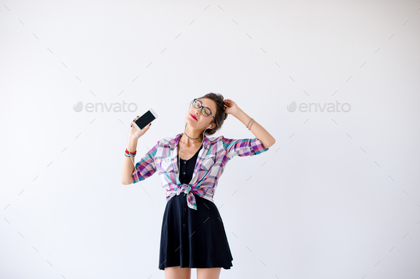 Girl in headphones and glasses listening to music and dancing - Stock Photo - Images