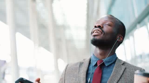 African American Businessman Listens To the Music and Dances While He Walks Along the Street. Happy alt