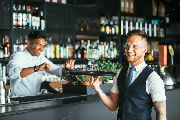 Smiling waiter with a cocktail