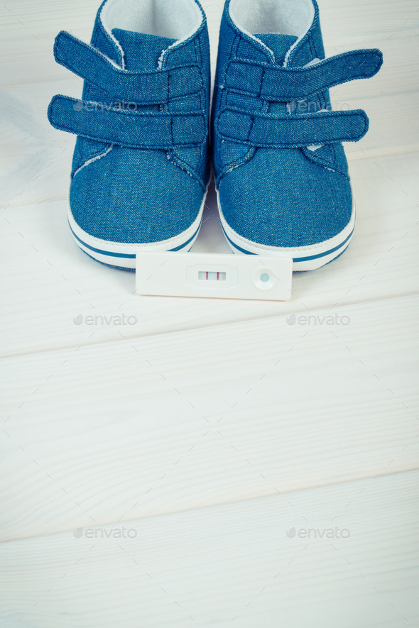 Pregnancy test with positive result and baby shoes for newborn - Stock Photo - Images