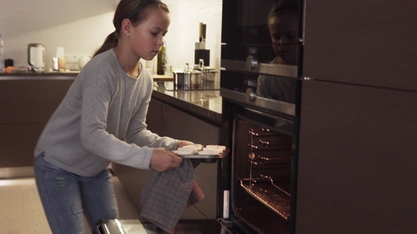Girl Puts Cookies in Oven for Baking in Modern Kitchen at Home