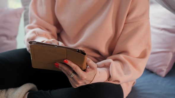 Woman Using Tablet Computer Touchscreen at Her Cozy Home. Female Hands with Digital Map-case in Bed alt