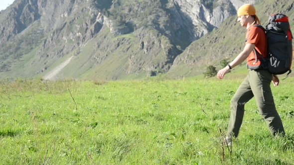 Hiking Man Walking on Green Mountain Meadow with Backpack. Summer Sport and Recreation Concept