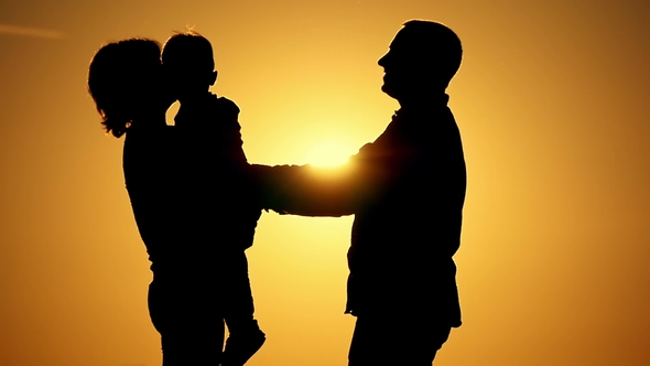 Silhouettes of Happy Family in Embrace on Sunset Background. Mom Holds ...