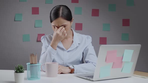 Asian woman working on a laptop tired and has eye pain sitting