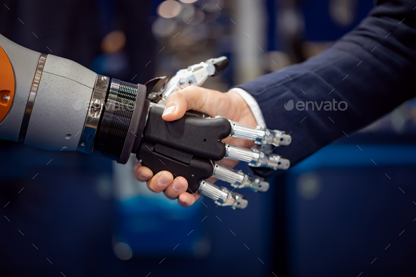Hand of a businessman shaking hands with a Android robot. - Stock Photo - Images