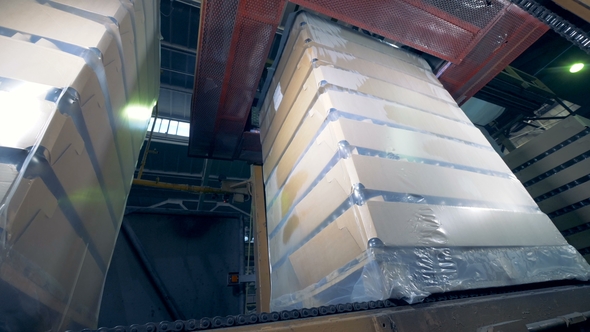 Wrapping Material Is Getting Tightened Around a Stack of Carton Boxes with Glass Bottles alt