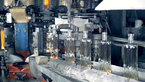 Newly-shaped Glass Bottles Are Relocating From the Glass-forming Machine Onto the Conveyor Belt alt