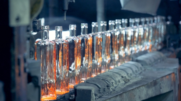 A Line of Incandescent Newly-made Glass Bottles Is Moving Along the Conveyor Belt alt