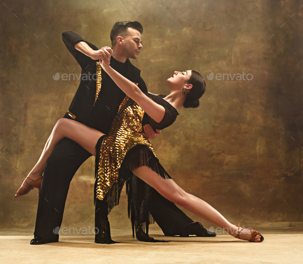 Dance ballroom couple in gold dress dancing on studio background. Stock Photo by master1305