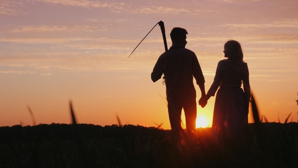 A Family of Farmers Enjoying the Sunset in the Field. A Man Is Holding a Scythe, Next To Him Is His alt