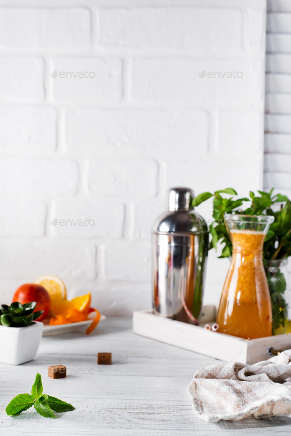 Orange lemonade in the decanter on a wooden tray and Cocktail shaker for preparing a summer cocktail - Stock Photo - Images