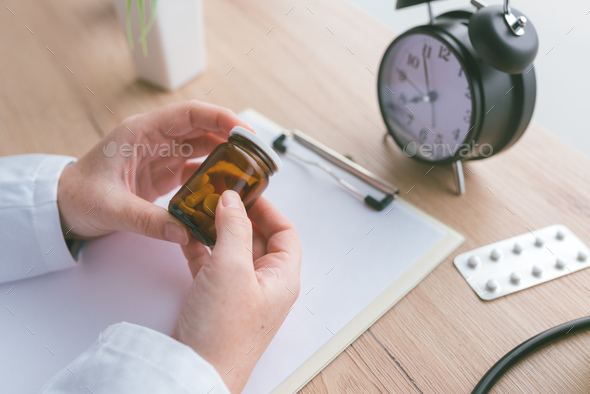 Female doctor holding unlabeled bottle of various pills and medi - Stock Photo - Images