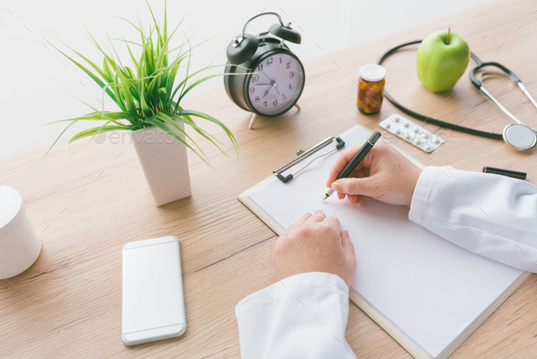 Female doctor writing notes on clipboard paper during medical ex - Stock Photo - Images