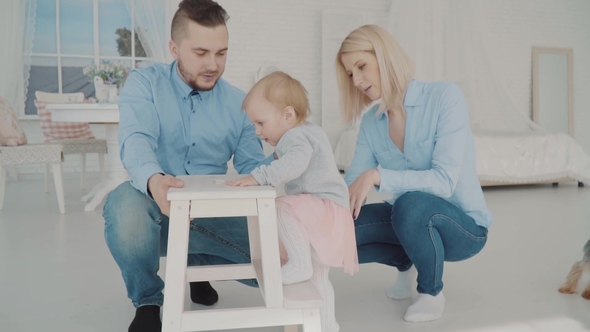 Happy Family with Their Lovely Baby Near the Chair.