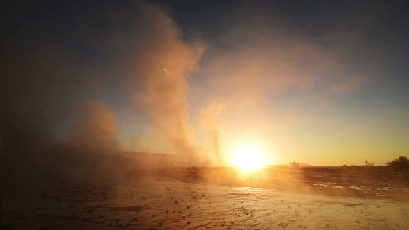 Eruption of Geyser in Iceland. Winter Cold Colors, Sun Lighting Through the Steam alt