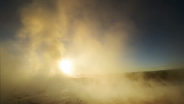 Eruption of Geyser in Iceland. Winter Cold Colors, Sun Lighting Through the Steam