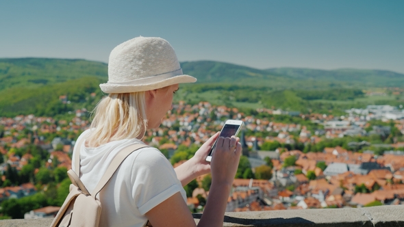 Woman Tourist Uses a Smartphone Against the Background of the Old Beautiful European City. Houses alt