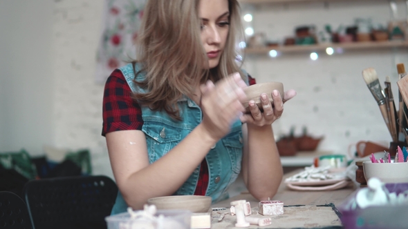 Young Woman Creates A Plate Of Clay In The Workshop. Girl Holding A 