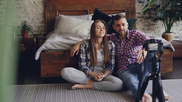 Adorable Couple Is Recording Video for Social Media with Camera, They Are Talking To Followers alt