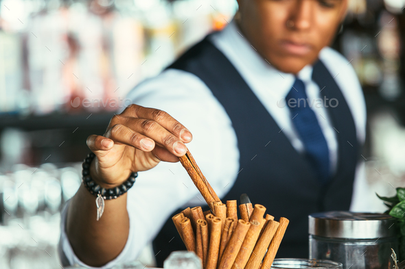 Detail of the hand of a bartender takes cinnamon stick - Stock Photo - Images