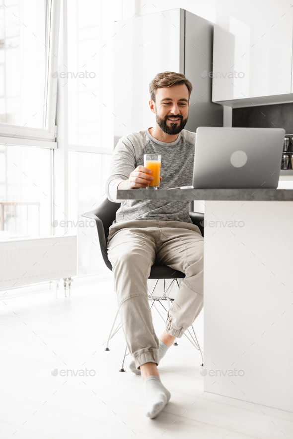 Portrait of a smiling young man drinking orange juice - Stock Photo - Images