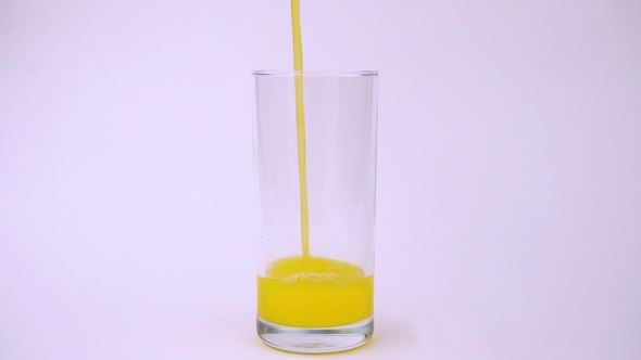 Slow Process of Pouring Yellow Orange in Transparent Glass on White Background
