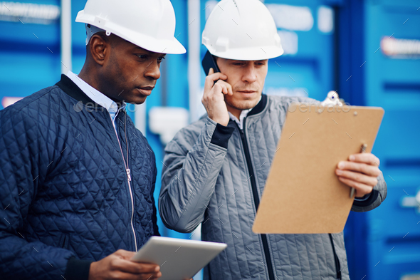 Engineers tracking freight together in a commercial shipping yard - Stock Photo - Images