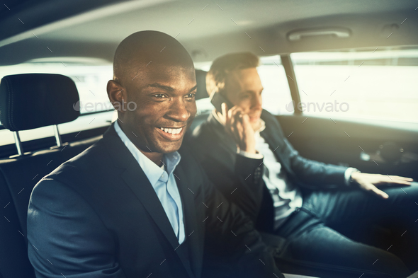 Smiling African businessman driving with a colleague to work - Stock Photo - Images