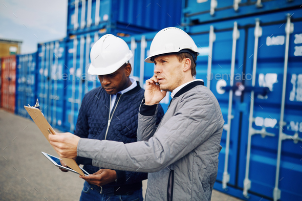 Engineers working in a large commercial freight shipping yard - Stock Photo - Images