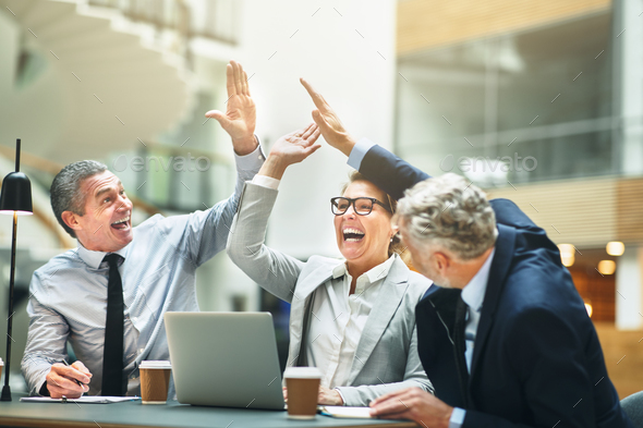 Mature businesspeople excitedly high fiving together in an office - Stock Photo - Images