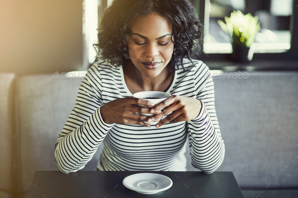 Young African woman enjoying a fresh cup of coffee - Stock Photo - Images