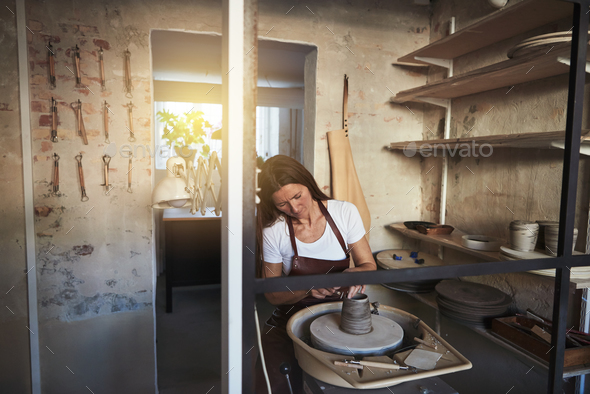 Female artisan creatively sculpting clay inside of her workshop - Stock Photo - Images