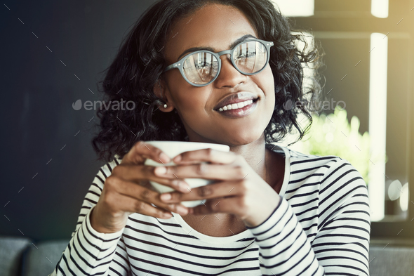 Smiling young African woman enjoying coffee in a cafe - Stock Photo - Images